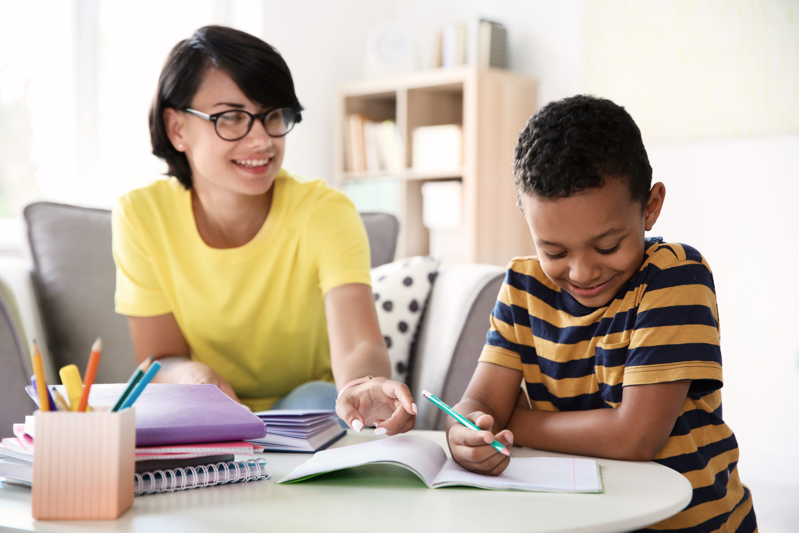 Young woman helping her child with homework at home. Elementary school